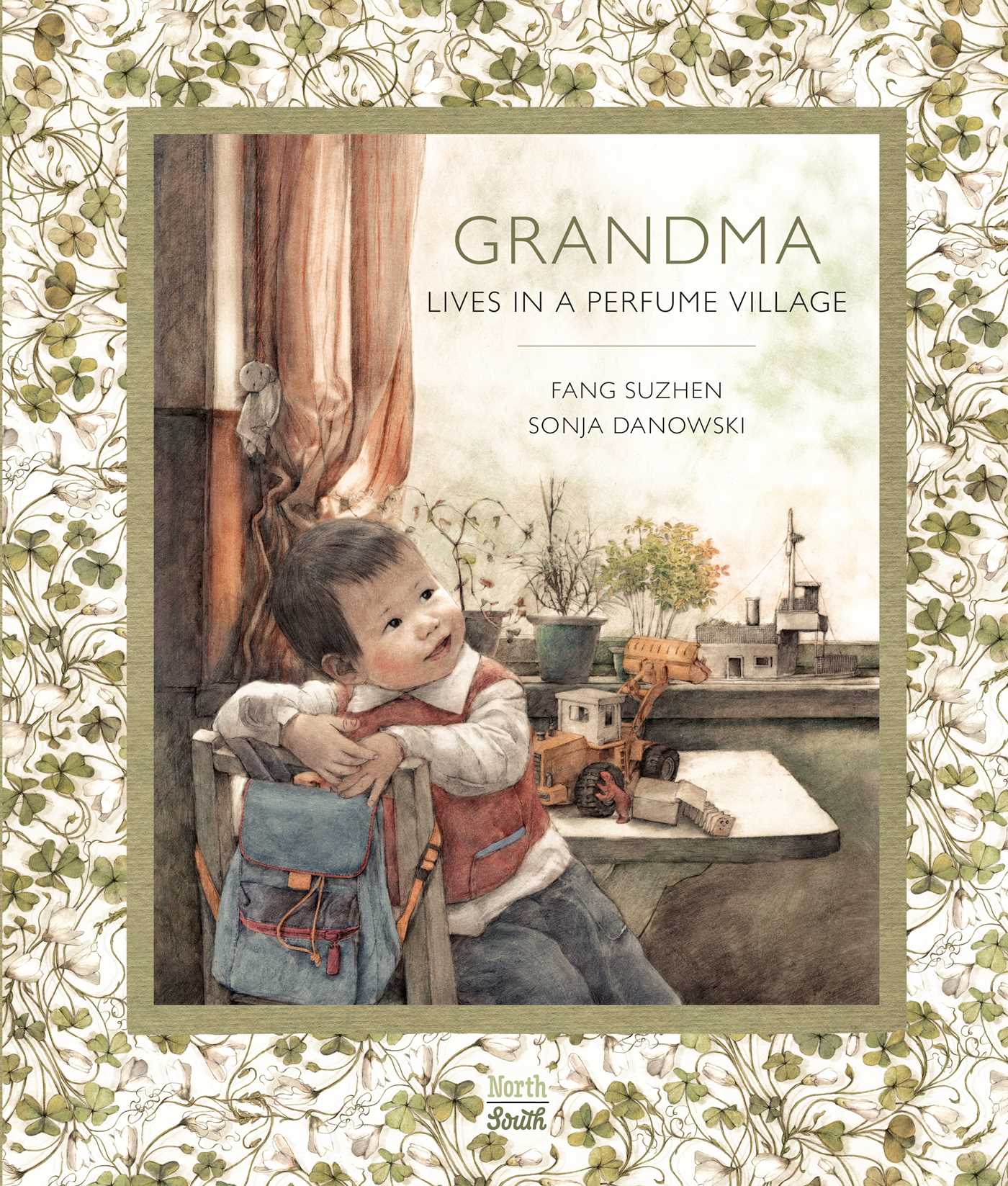 Cover of Grandma Lives in a Perfume Village featuring an illustration of a small child sitting at a table near a window with trinkets on the sill on a chair with a backpack slung over the back. The illustration is in a green frame and surrounded by a pattern of green clovers.