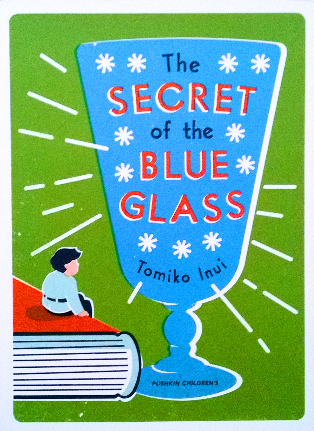 Cover for The Secret of the Blue Glass featuring an illustration of a small boy sitting on a book looking at a large graphic of a blue glass with flourishes indicating it is shining. The background is green.